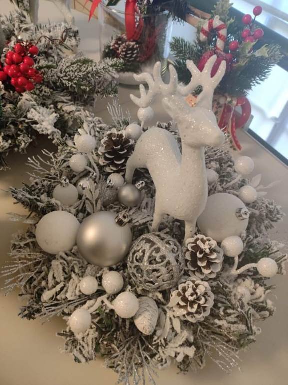 A white reindeer with silver ornaments and pine cones
Description automatically generated